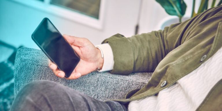 Two people holding phones over two cups of coffee.