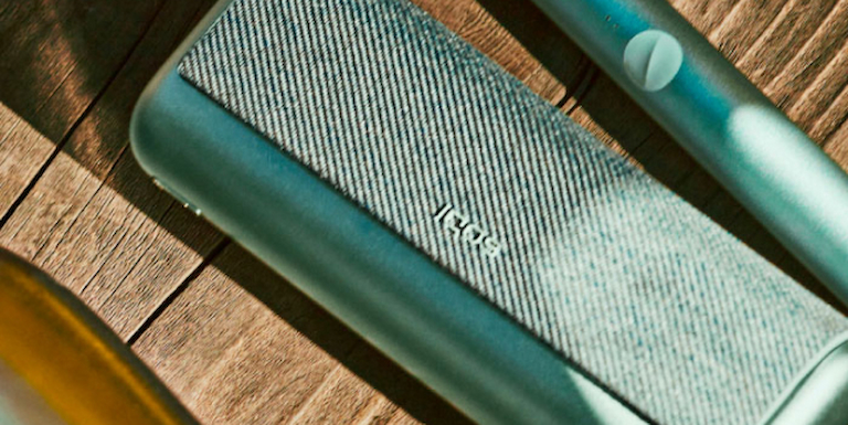 Hands holding smartphones and one IQOS device.