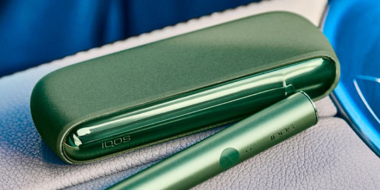 A person holding an unopened IQOS device box.